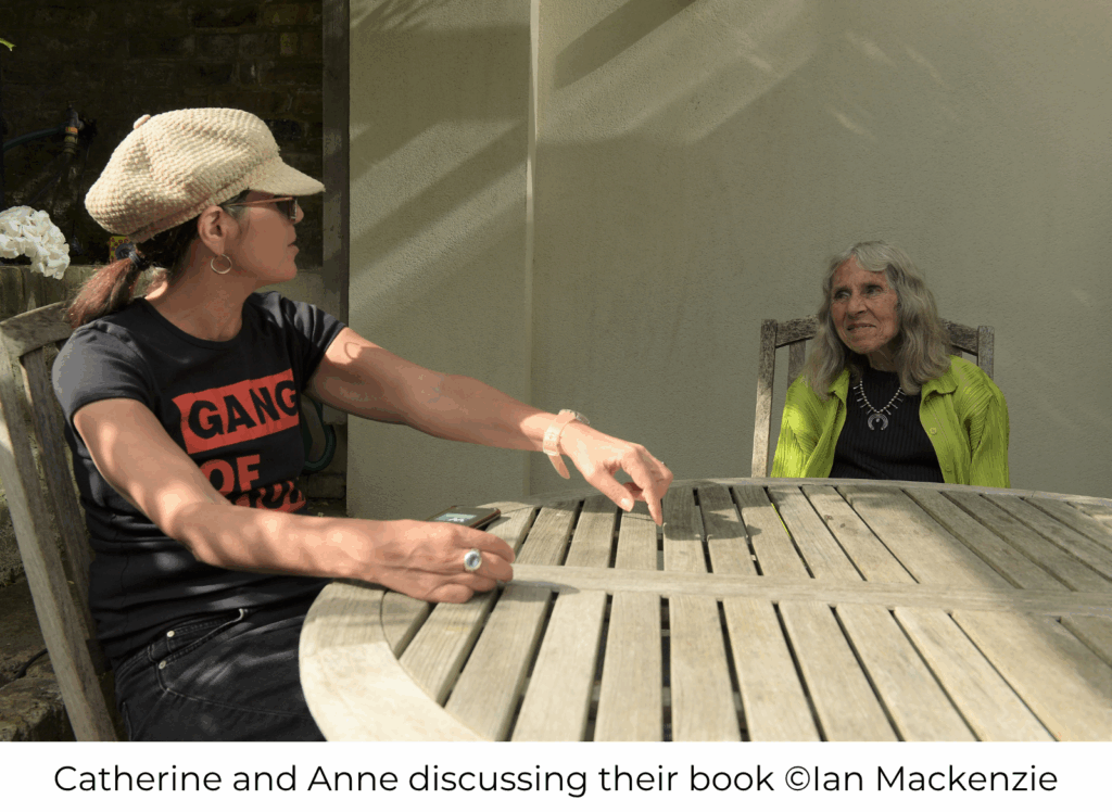 Catherine and Anne sat an outdoor table discussing their book during lockdown. Photo credit: Ian Mackenzie