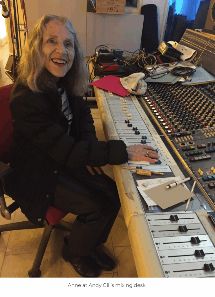 Anne smiling broadly as she sits at Andy Gill's complicated looking sound desk